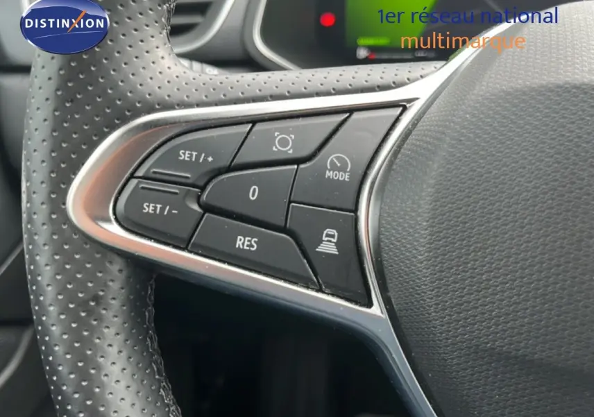 Gros plan sur les commandes à gauche du volant perforé du Renault Symbioz gris Cassiopée, boutons de régulateur et assistance.