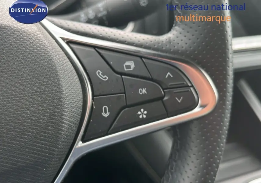 Gros plan sur les commandes multifonctions noires du volant perforé d’une Renault Symbioz gris cassiopée métal.