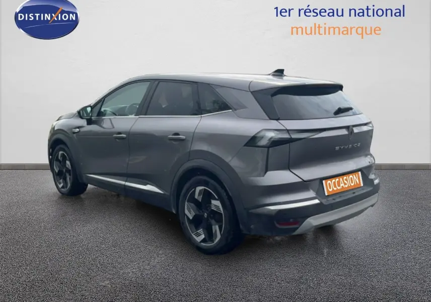 Vue 3/4 arrière droite d’un Renault Symbioz gris cassiopée métallisé avec jantes noires et grises, sur fond neutre.