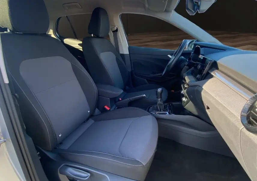 Vue intérieure côté gauche de la Skoda Fabia 2024, sièges tissu gris avec surpiqûres et console centrale noire.