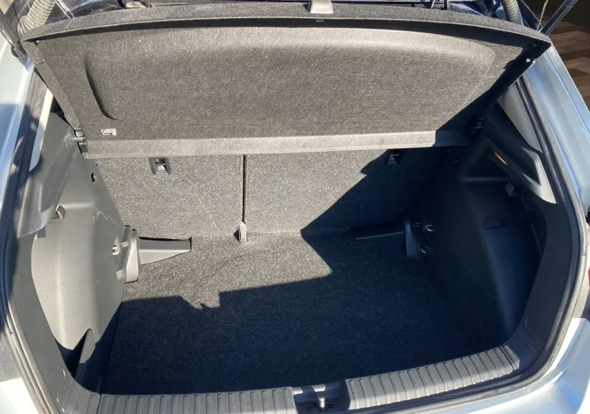 Coffre ouvert vu de dessus d'une Skoda Fabia 2024 gris/noir, montrant l'espace de rangement et la moquette intérieure.