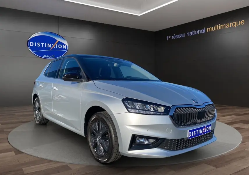 Vue 3/4 avant droite d'une Skoda Fabia 2024 gris clair avec toit et rétroviseurs noirs, calandre noire distinctive.