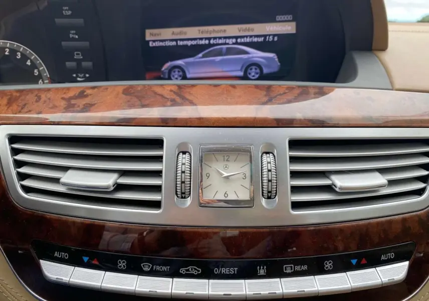 Plan rapproché du tableau de bord en bois Designo de la Mercedes Classe S 600 L, avec horloge analogique et commandes climatisation.