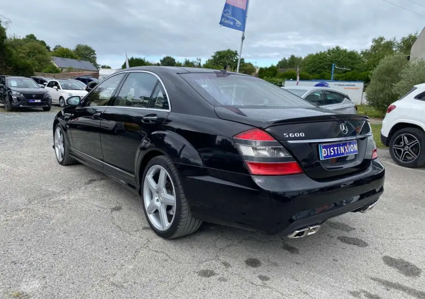 Vue 3/4 arrière droite d'une Mercedes Classe S 600 L noire avec jantes AMG 20 pouces et double sortie d'échappement AMG.