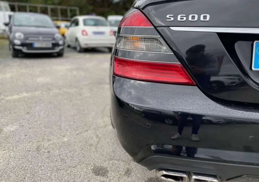Gros plan sur l'arrière droit noir d'une Mercedes Classe S 600 L avec feux et double sortie d'échappement AMG visibles.