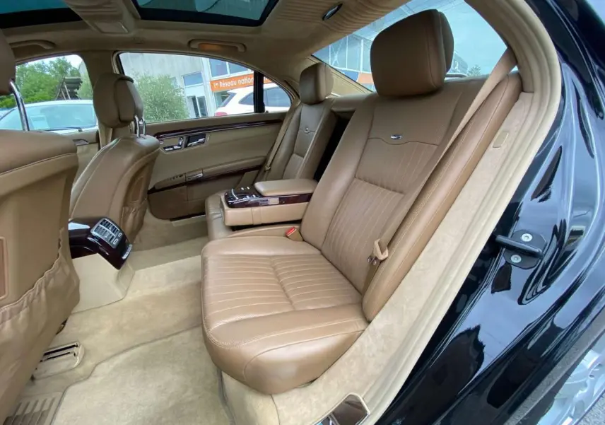 Vue côté droit de l'intérieur arrière d'une Mercedes Classe S 600 L noire avec sellerie cuir Designo beige et toit ouvrant panoramique.