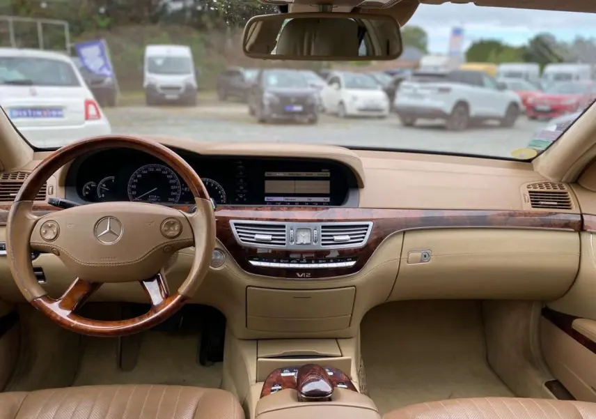 Intérieur beige clair d'une Mercedes Classe S 600 L 2007, vue frontale sur le tableau de bord en bois Designo et volant cuir-bois.