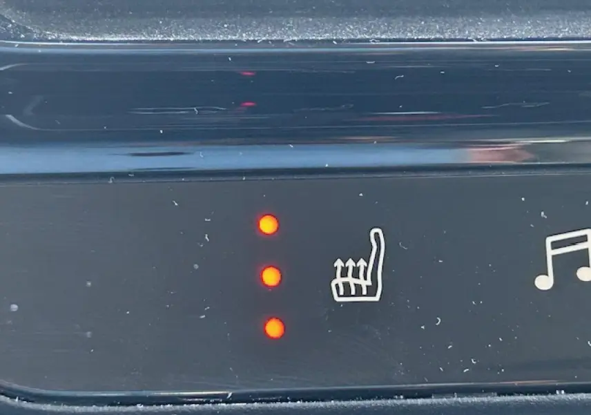 Gros plan sur le bouton de chauffage de siège avec trois voyants rouges allumés dans un Citroën C5 Aircross gris platinium.