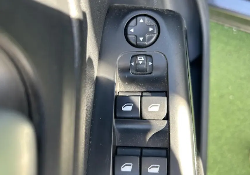 Gros plan sur les commandes des vitres électriques côté conducteur du Citroën C5 Aircross gris platinium, avec réglage des rétroviseurs.