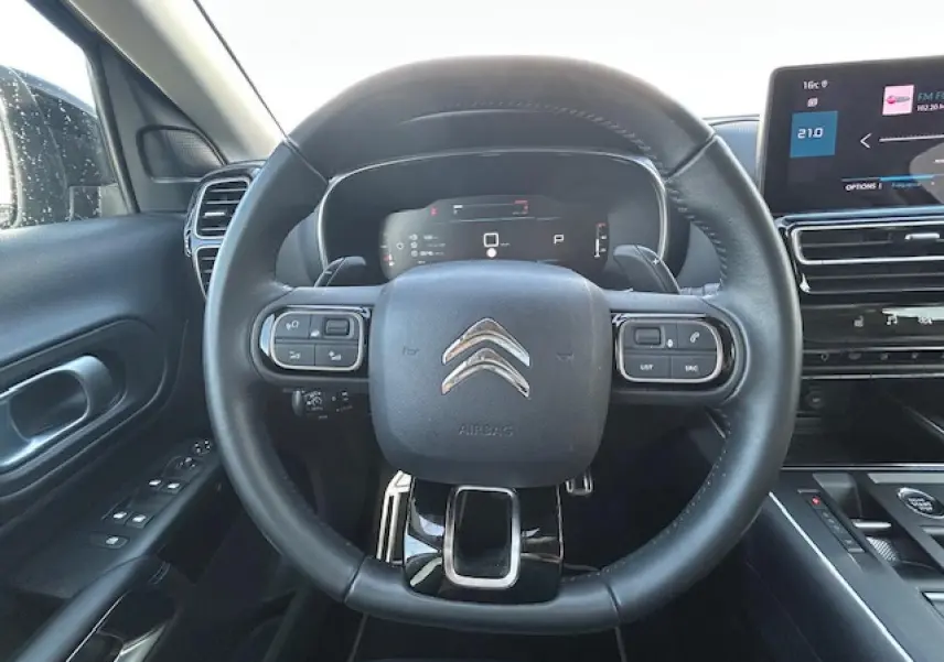 Vue intérieure centrée sur le volant cuir du Citroën C5 Aircross 2022 avec tableau de bord numérique et écran tactile.