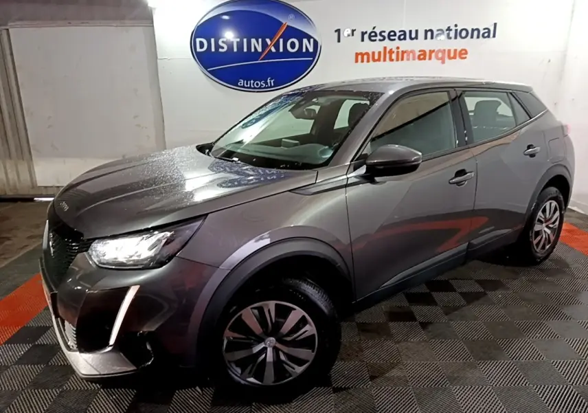Peugeot 2008 gris clair vue 3/4 avant droit, avec phares LED et jantes alliage distinctives, en intérieur showroom.