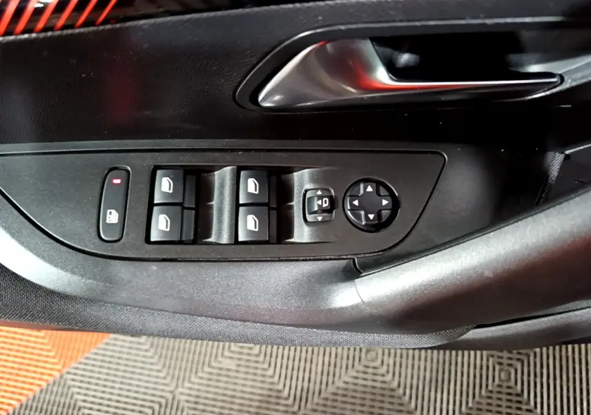Gros plan sur les commandes des vitres et rétroviseurs sur la porte côté gauche d’un Peugeot 2008 gris clair.