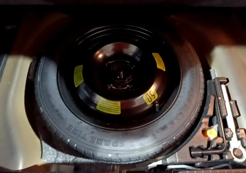 Vue rapprochée de la roue de secours noire dans le coffre d'une Peugeot 2008 gris clair de 2021.