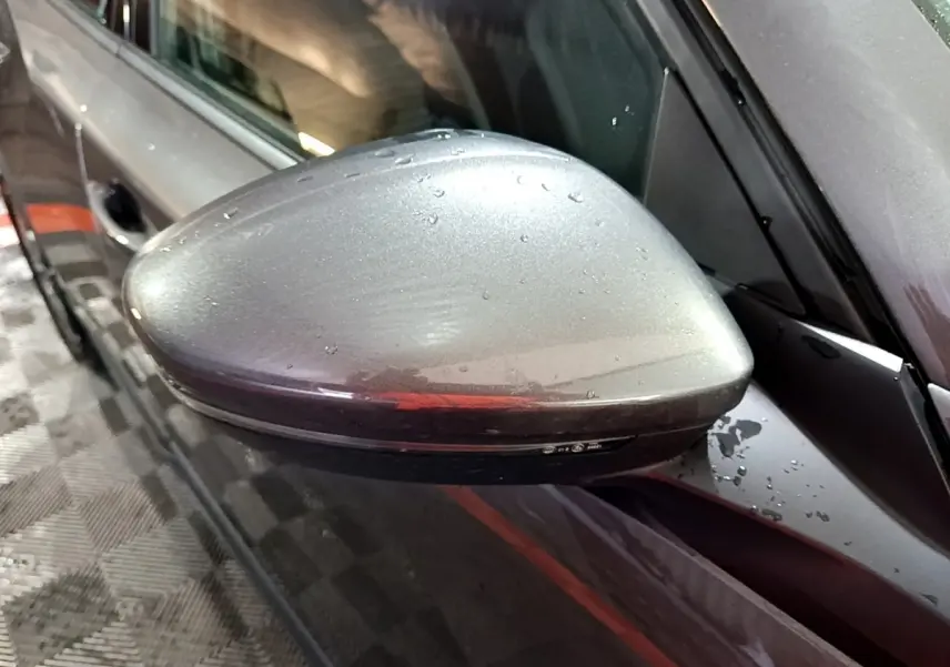Rétroviseur côté gauche gris clair de Peugeot 2008 2021 avec gouttes d'eau, vue rapprochée en légère plongée.
