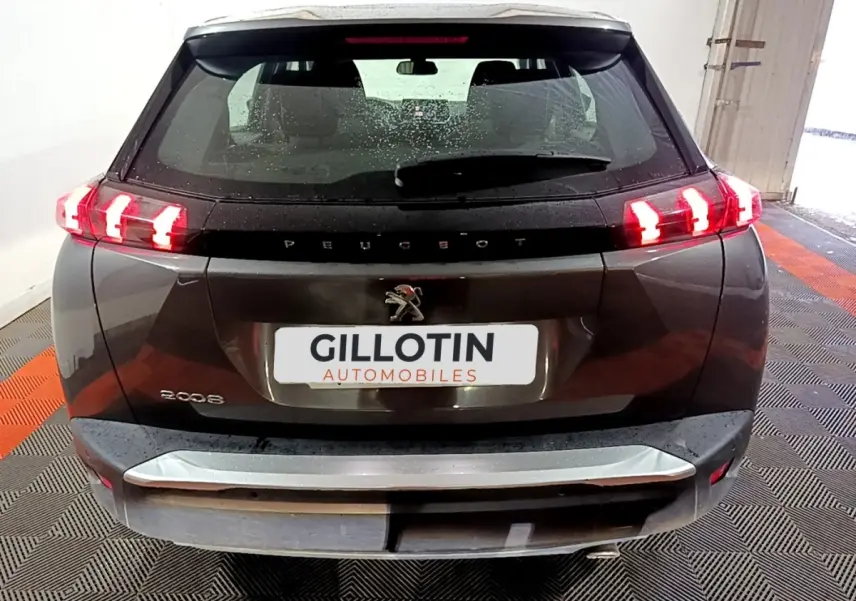 Vue arrière d’un Peugeot 2008 gris clair avec feux arrière LED allumés dans un garage.