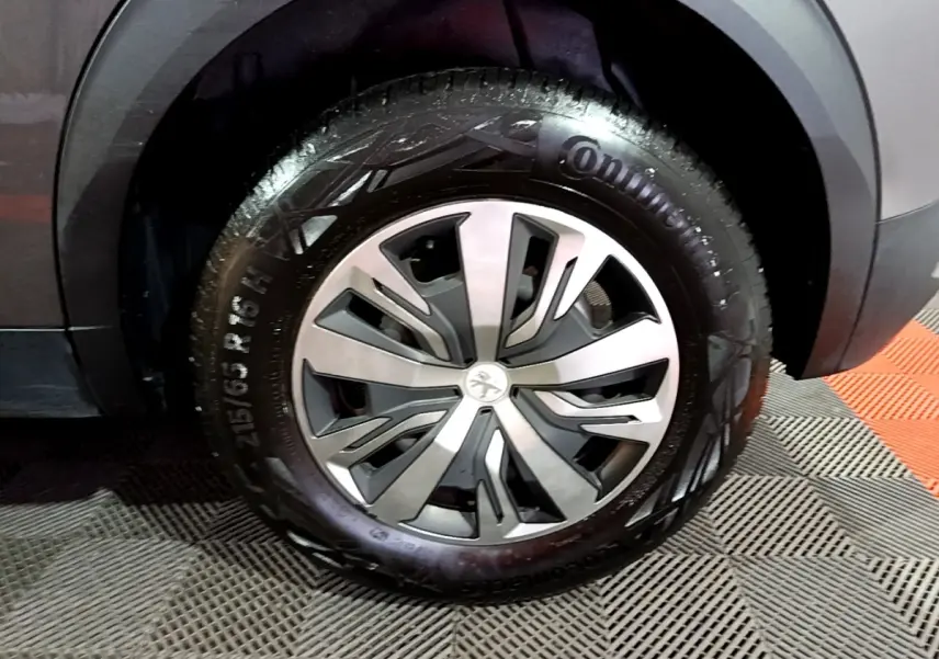Gros plan sur la roue avant droite d’un Peugeot 2008 gris clair, avec jante alliage et pneu Continental visible.