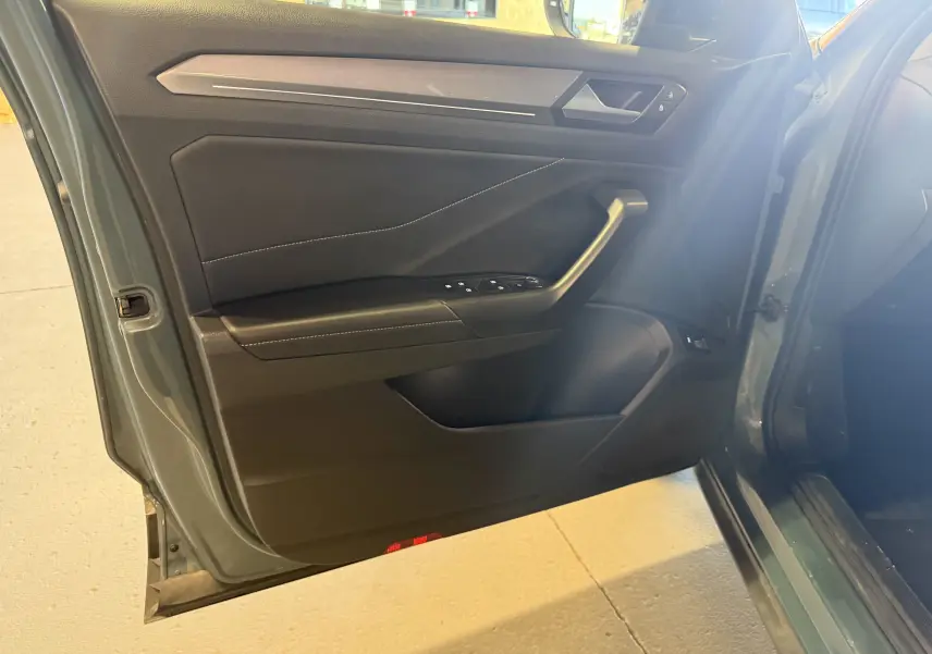 Vue rapprochée de la porte avant gauche bleu du Volkswagen T-Roc 2022, avec commandes de vitres et poignée intégrée.