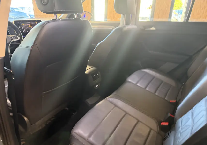 Vue intérieure arrière du Volkswagen T-Roc 2.0 TDI 150 DSG7, sièges en cuir noir et tableau de bord avec écran tactile visible.