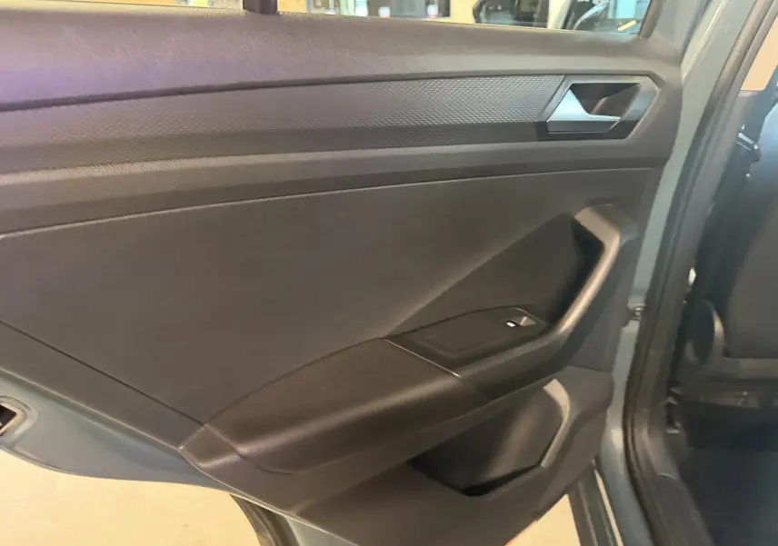 Vue intérieure du panneau de porte arrière gauche du Volkswagen T-Roc bleu 2022, avec commande de fenêtre visible.