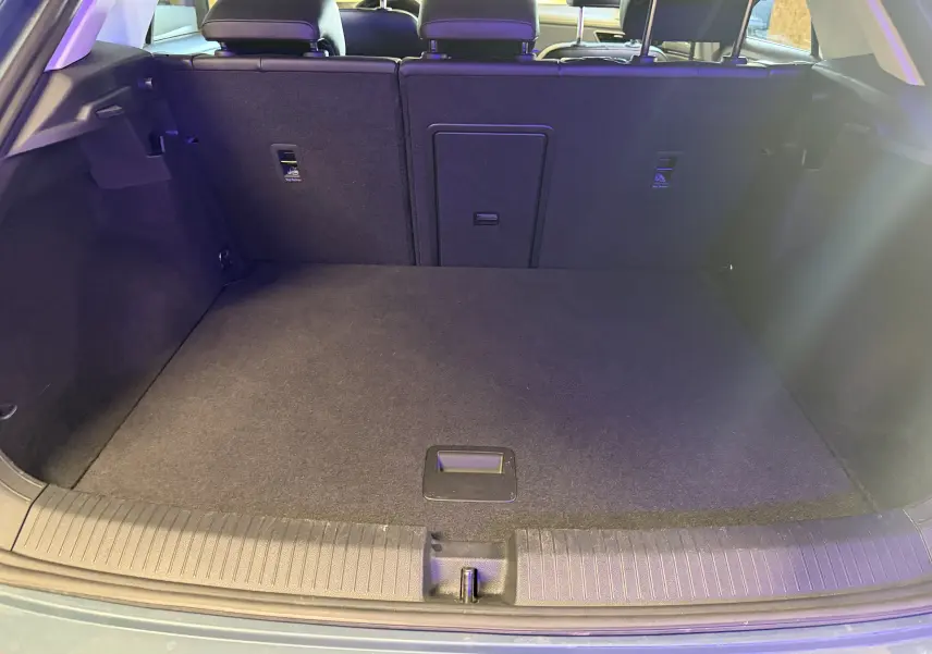 Vue du coffre ouvert du Volkswagen T-Roc bleu 2022, montrant l'espace de chargement et le dossier des sièges arrière.