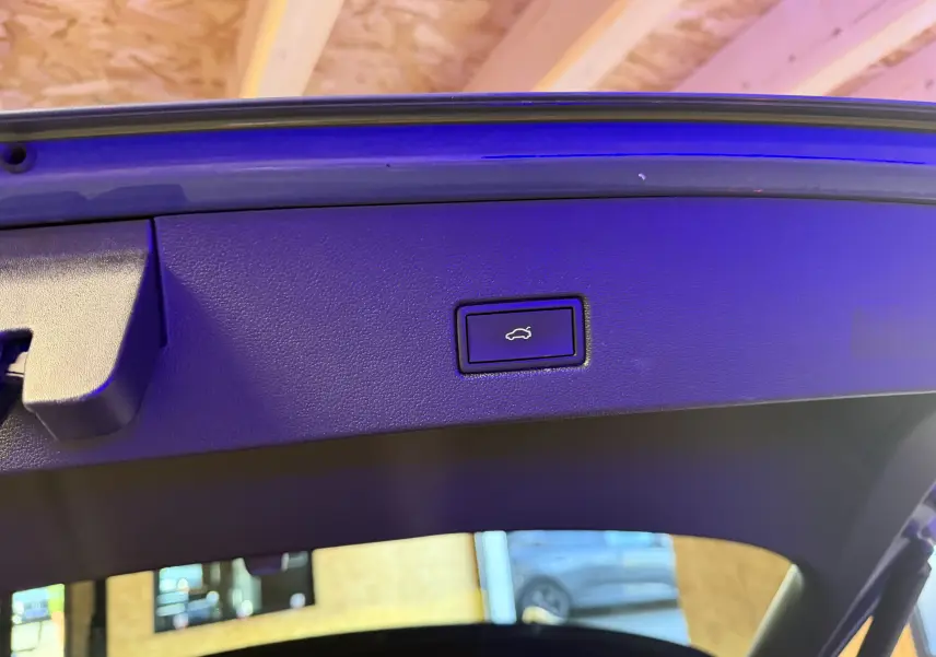 Bouton d'ouverture électrique du hayon sur la partie intérieure du coffre d'un Volkswagen T-Roc bleu 2022.