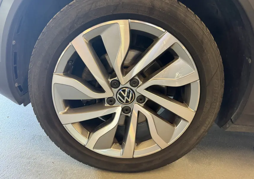 Gros plan sur la jante alliage argentée du Volkswagen T-Roc bleu 2022, mettant en valeur le logo VW central.