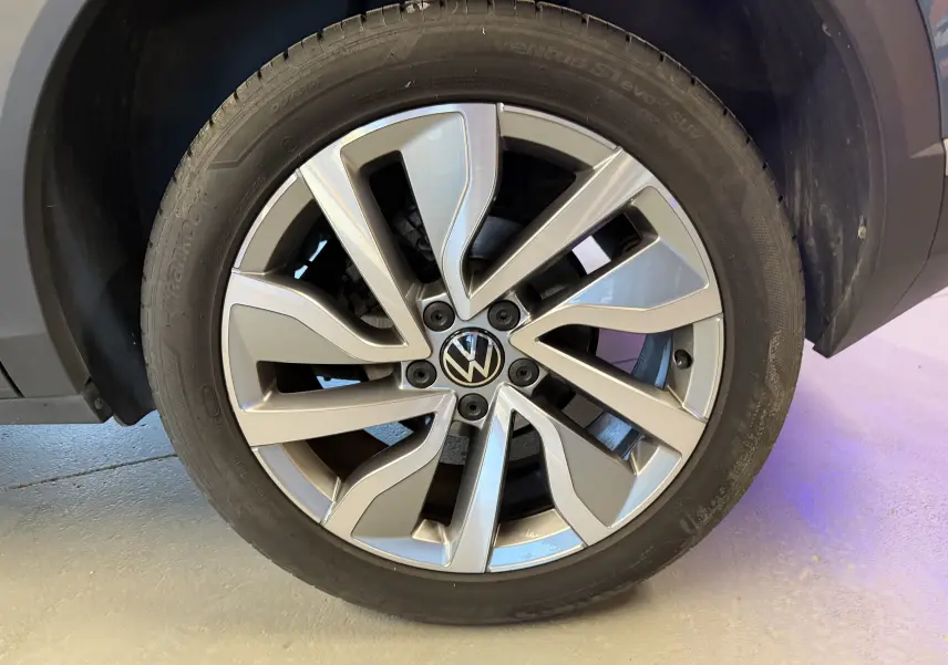 Gros plan sur la roue avant droite du Volkswagen T-Roc bleu 2.0 TDI 150 DSG7 avec jante alliage distinctive.