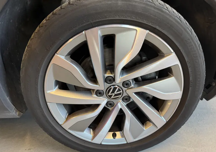 Gros plan sur la jante alliage argentée au design moderne du Volkswagen T-Roc bleu, roue avant droite visible.