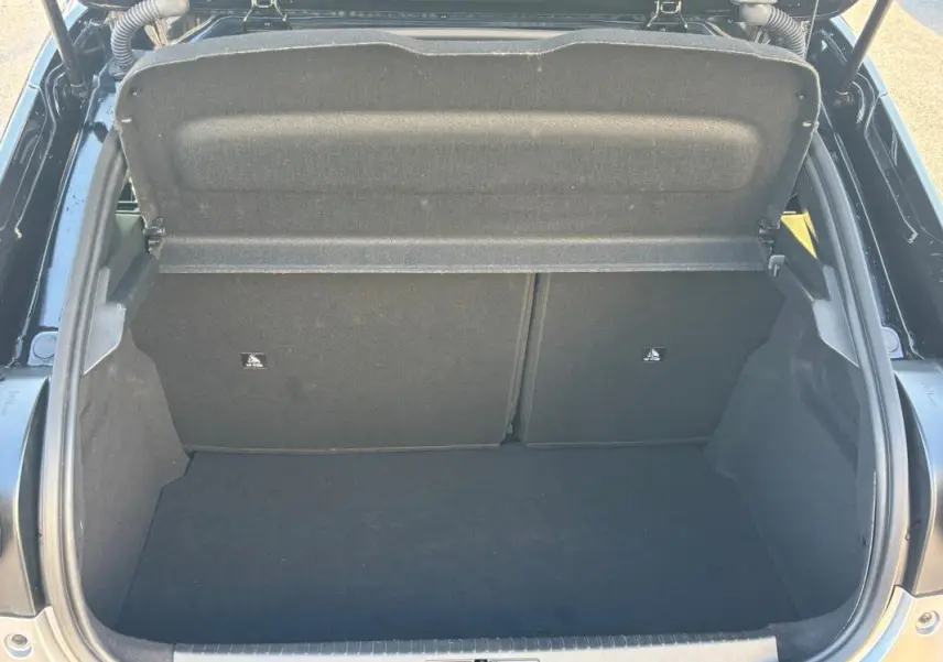 Coffre ouvert vu de l'arrière d'une Lancia Ypsilon gris 2025, montrant l'espace de chargement vide et la tablette arrière.