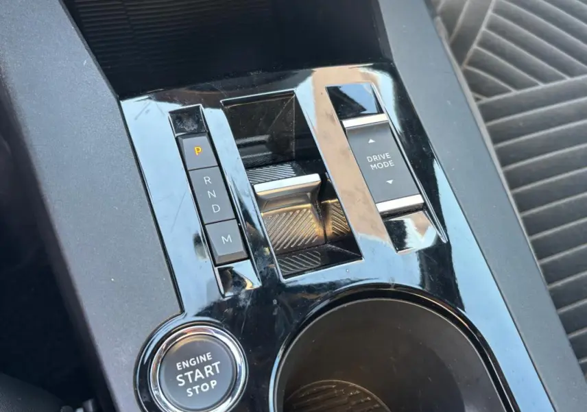 Gros plan sur la console centrale noire brillante de la Lancia Ypsilon 1.2 Ibrida avec bouton start/stop et commandes boîte auto.