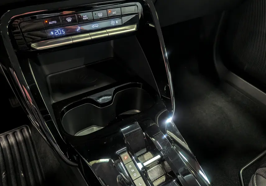 Gros plan sur la console centrale noire brillante de la Citroën C3 Aircross hybride 2026 avec commandes climatisation et levier de boîte auto.