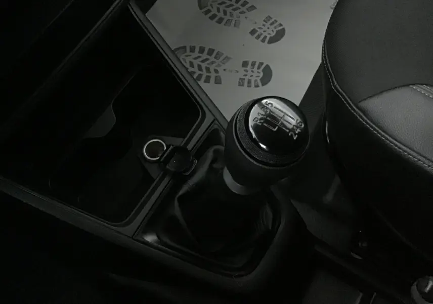 Le levier de vitesses manuel en gros plan dans l'habitacle sombre d'un Renault Express Van blanc.