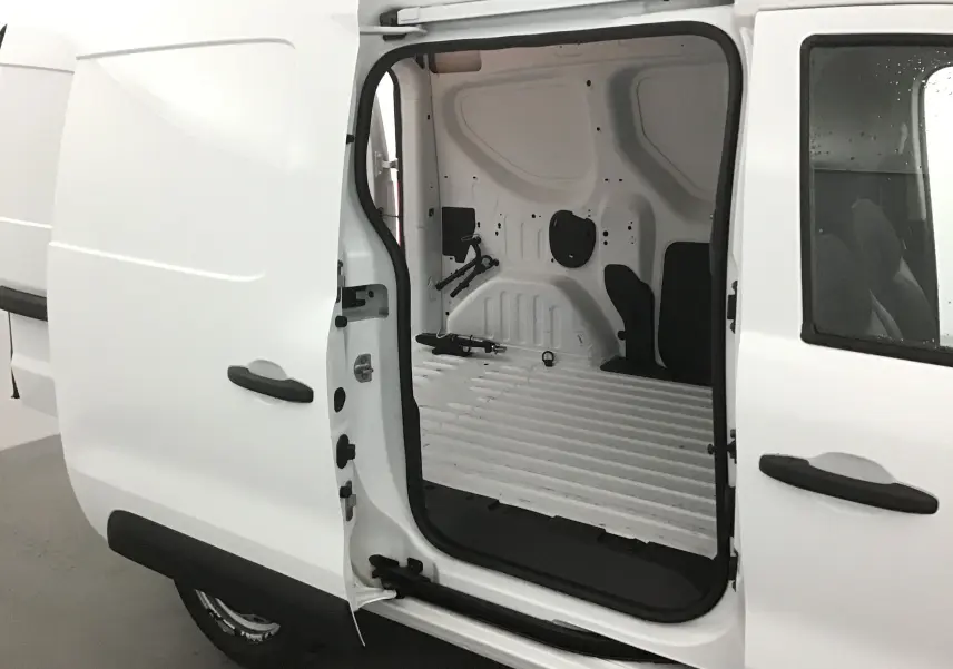 Vue latérale côté droit du Renault Express Van blanc 2021 avec porte coulissante ouverte montrant l’espace de chargement vide.