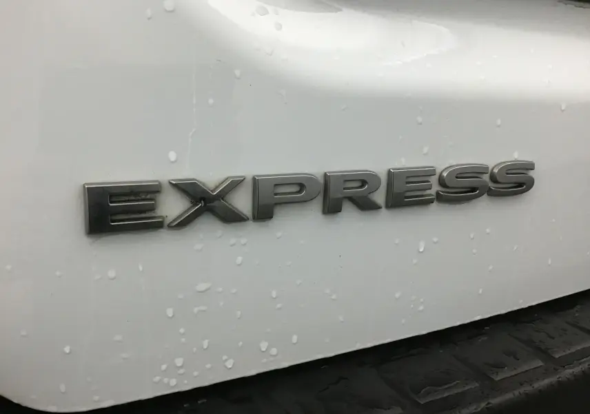 Gros plan sur l’inscription Express en lettres métalliques sur la partie arrière blanche du Renault Express Van.