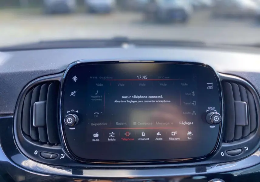 Écran tactile central du tableau de bord de la Fiat 500 noire 2024 avec commandes multimédia et ventilation intégrée.