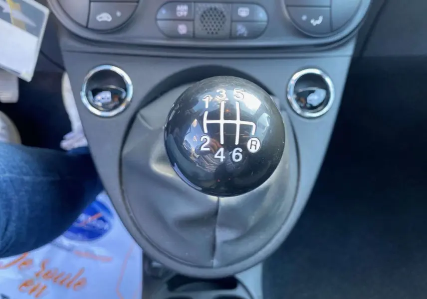 Gros plan sur le levier de vitesses manuel noir de la FIAT 500 2024, mettant en valeur la grille des six rapports.