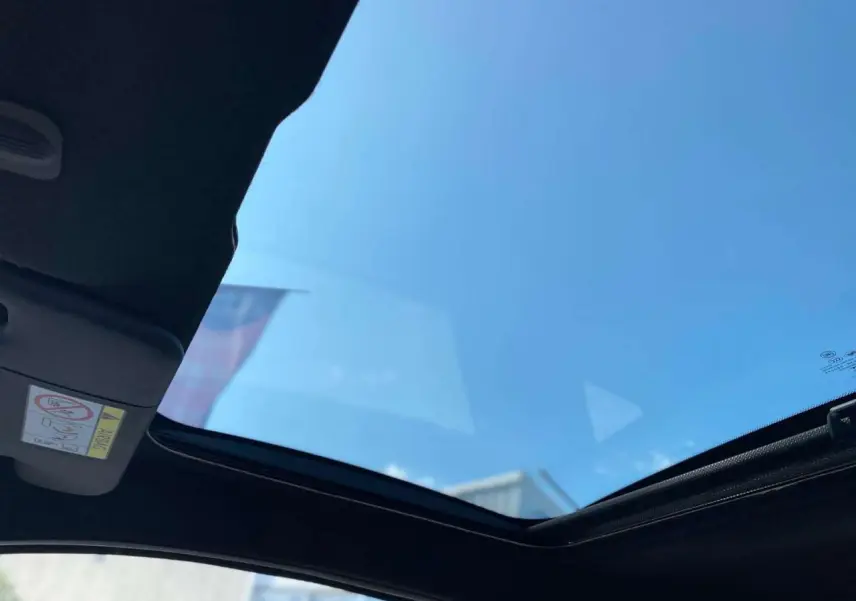 Toit vitré panoramique fixe de la FIAT 500 noire vue de l'intérieur vers le ciel bleu.