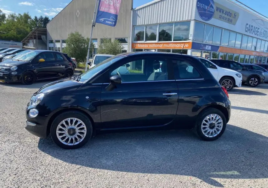 Profil latéral droit d'une FIAT 500 noire 2024 avec jantes alliage 16'' Spider, stationnée en extérieur.
