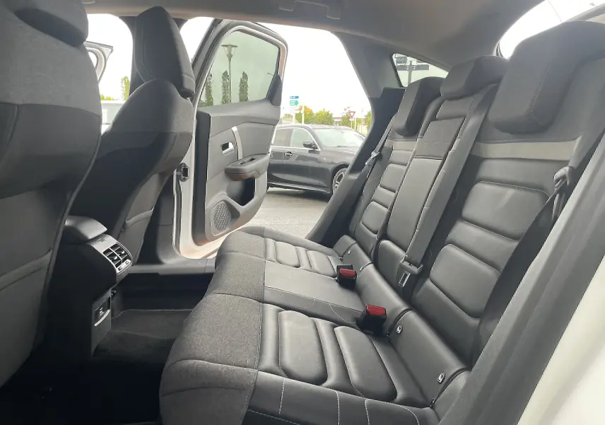 Vue intérieure arrière droite d'une Citroën C4 blanche 2022, sièges arrière en tissu gris noir avec ceintures de sécurité visibles.