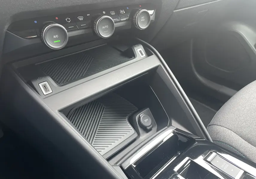Vue rapprochée de la console centrale noire avec commandes climatisation et prise 12V d'une Citroën C4 blanche 2022.