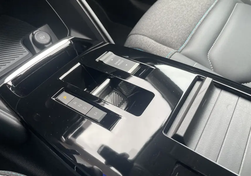 Gros plan sur la console centrale noire brillante de la Citroën C4 2022, avec levier de vitesses automatique et bouton Drive Mode.