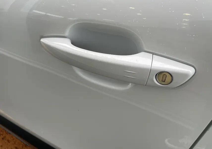 Poignée de porte blanche côté droit de la Citroën C4 1.2 PureTech 130 Shine avec serrure visible sur la portière.