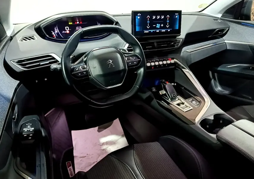 Vue intérieure avant du Peugeot 3008 noir 2022, volant cuir multifonctions et écran tactile central lumineux.