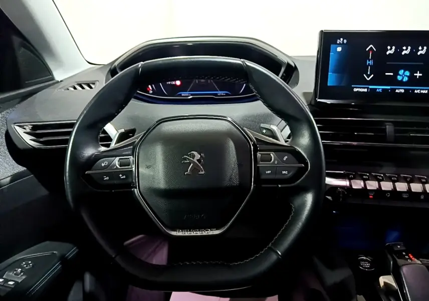 Vue centrée sur le volant cuir noir multifonctions du Peugeot 3008 2022 avec tableau de bord digital et écran tactile.