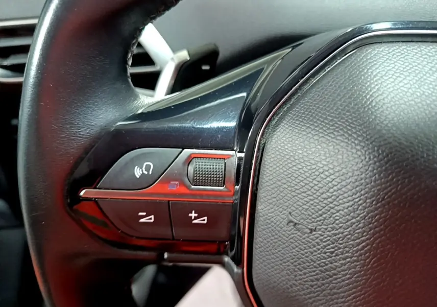 Gros plan sur le volant cuir noir côté gauche du Peugeot 3008 2022 avec commandes multifonctions intégrées.