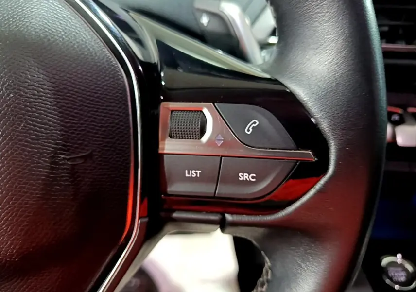 Gros plan sur le volant cuir noir de la Peugeot 3008 2022, avec commandes multifonctions et bouton appel téléphonique.