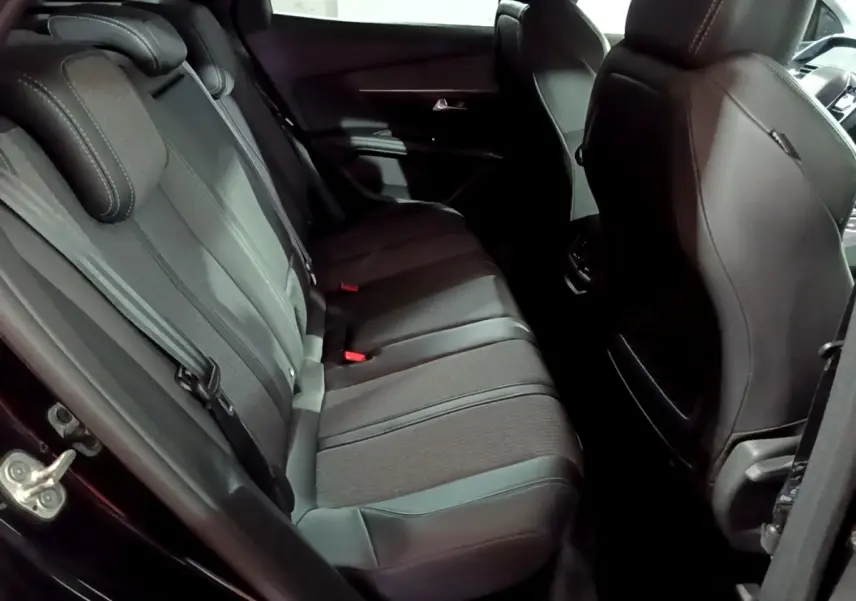 Vue intérieure côté arrière gauche du Peugeot 3008 noir, montrant la banquette arrière en tissu et cuir avec ceintures de sécurité.