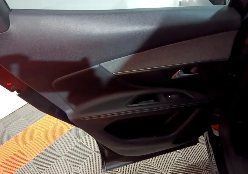 Vue rapprochée de la porte arrière gauche noire du Peugeot 3008 2022, avec garniture en cuir et commandes de fenêtre.