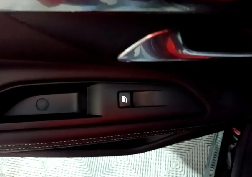 Détail de la commande de lève-vitre sur la porte côté gauche d’un Peugeot 3008 noir, finition cuir.