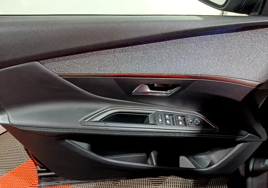 Vue du panneau de porte avant gauche noir avec commandes électriques et poignée chromée sur Peugeot 3008 2022.